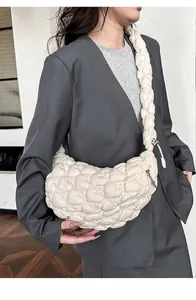 Close-up of a white quilted dumpling shoulder bag with soft cloud-like pleated texture