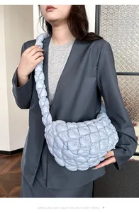 Close-up of light blue quilted cloud bag with bubbly texture on a model in a grey suit