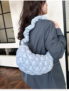 Close-up of light blue cloud bag featuring heart quilting and soft braided strap