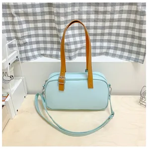 Détail du sac Boston bleu clair en similicuir avec poignées jaunes et bandoulière