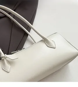 Detail of soft cream leather texture and durable stitching on minimalist baguette bag