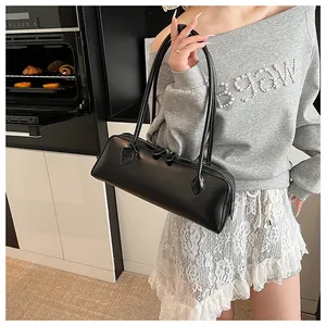Detail view of a black faux leather baguette bag with long handles in a modern kitchen
