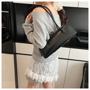 Close-up of minimalist black baguette bag shoulder strap on model in modern home