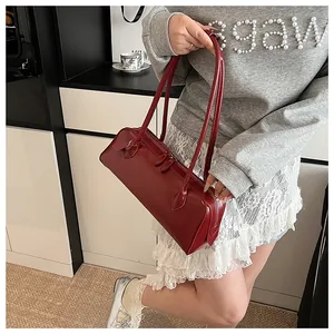 Close-up of vintage burgundy baguette bag with long handles shown on model shoulder