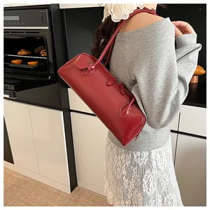 Detail view of the vintage red baguette bag with long handle and leather texture