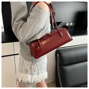 Detail view of burgundy long baguette bag with dual straps worn by a model