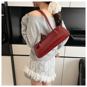 Detail view of smooth deep red leather shoulder bag with metallic zipper and long strap