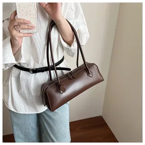 Detail of a dark brown glossy leather baguette bag with dual long shoulder handles
