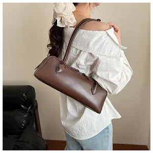 Brown leather baguette bag worn by model showing slim long shoulder strap detail