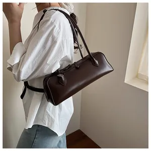 Brown leather baguette bag with long straps shown on shoulder for professional look