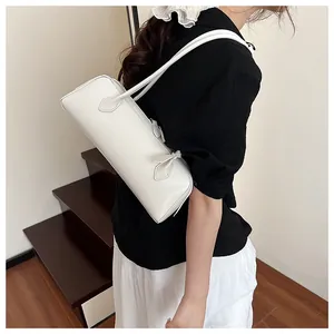 White faux leather baguette bag worn by a model on a modern staircase background