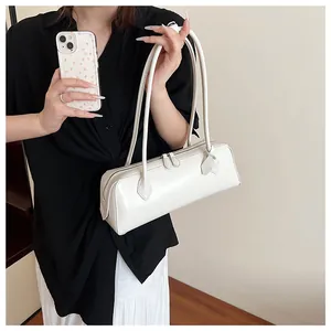 Minimalist white baguette bag with double zipper and slim straps worn over the shoulder