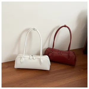 Detail view of rectangular leather bag showing dual zippers and long shoulder straps