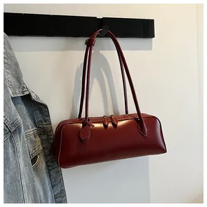 Detailed view of deep red baguette bag hanging on a hook next to a denim jacket