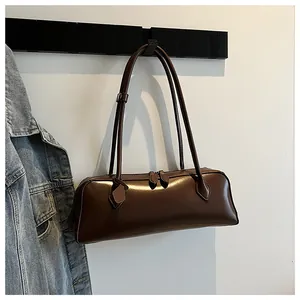 Detail view of a vintage dark brown glossy baguette bag hanging on a minimalist rack