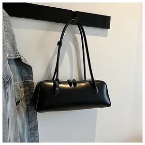 Close-up of black glossy baguette bag featuring dual leaf-shaped zippers and long straps