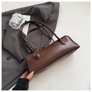 Detail of a brown matte leather baguette bag with long straps and top zipper closure