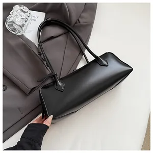 Detail of minimalist black baguette bag with long handles on a grey suit background