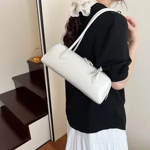 Minimalist white leather cylinder baguette bag styled as a shoulder underarm bag