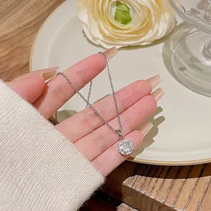 Collier élégant en acier titane avec pendentif en zircon étincelant tenu à la main de près