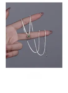 Dettaglio della collana in argento s925 con ciondolo in zircone verde oliva sulla mano