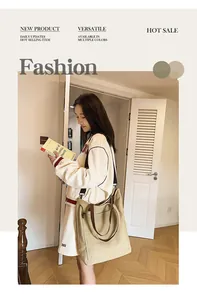 Close-up of a large khaki canvas tote bag worn by a model in a stylish indoor setting