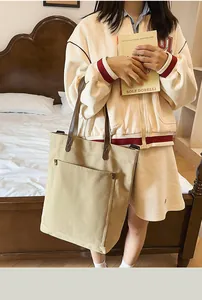 Large beige canvas tote bag with brown straps shown in a lifestyle bedroom setting