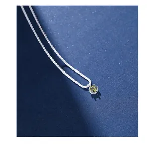 Macro shot of silver necklace featuring a round olive green zircon in a multi-prong setting