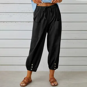 Dettaglio di pantaloni larghi neri in cotone e lino da donna con bottoni sull'orlo