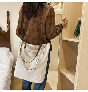 Detailed view of the large capacity canvas tote bag worn by a model in a cozy room