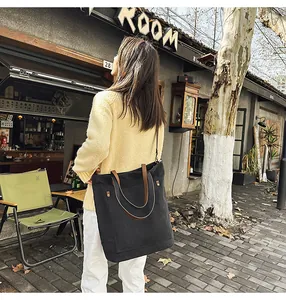 Woman carrying a large black canvas tote bag in an urban street setting