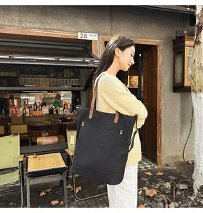 Stylish large black canvas tote bag for women shown in a casual outdoor street scene