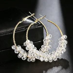Detailed view of elegant large gold hoop earrings with clear faceted crystal beads