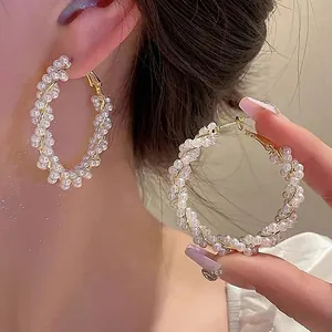 Close-up of large twisted hoop earrings adorned with white pearls on a gold frame