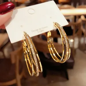 Macro detail view of luxury gold triple hoop earrings with pavé-set cubic zirconia