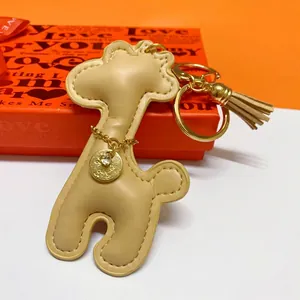 Macro view of cute beige leather giraffe keychain featuring gold tassel and charm