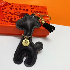 Detailed view of a black leather giraffe keychain with a gold tassel and charm