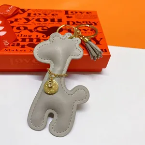 Close-up of a stylish gray leather giraffe keychain with a gold charm and tassel detail