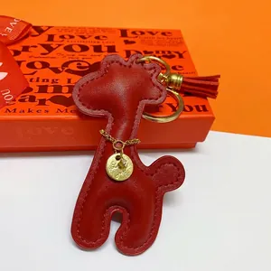 Detailed close-up view of a cute red leather giraffe keychain with a golden tassel
