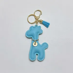Detail of cute light blue leather giraffe keychain with gold hardware and tassel