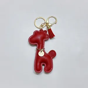 Detailed close-up of a red leather giraffe bag charm with gold tassel and Lucky Girl tag