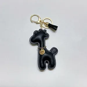 Detailed view of a black leather giraffe keychain charm with gold hardware and tassel