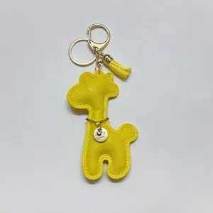 Detail of a bright yellow giraffe bag charm with golden tassel and rhinestone accent
