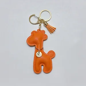Detailed view of bright orange leather giraffe keychain with gold tassel and charm
