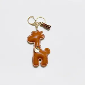 Adorable brown faux leather cartoon giraffe keychain featuring a gold tassel charm