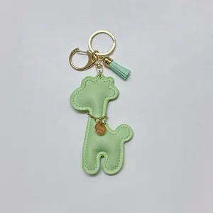 Detail view of a mint green cartoon giraffe faux leather keychain with gold hardware and tassel.