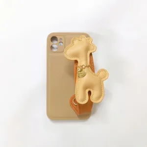 Detailed view of a cute 3D beige giraffe leather charm with a brown wrist strap for phone cases.