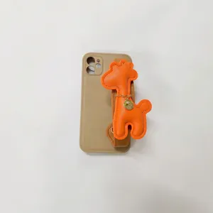 Detailed view of a cute orange leather giraffe wrist strap on a khaki mobile phone case