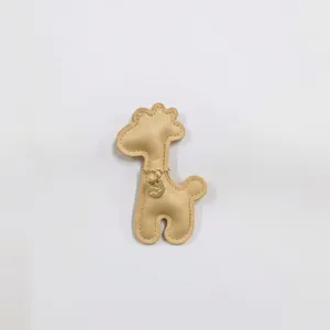 Close-up of a cute beige leather cartoon giraffe charm featuring a gold metal tag