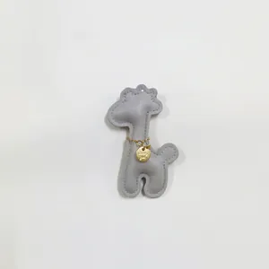 Detail shot of a cute gray leather giraffe charm with gold chain accessory for bags